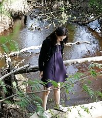 Teenage brunette peeing into a river in the park